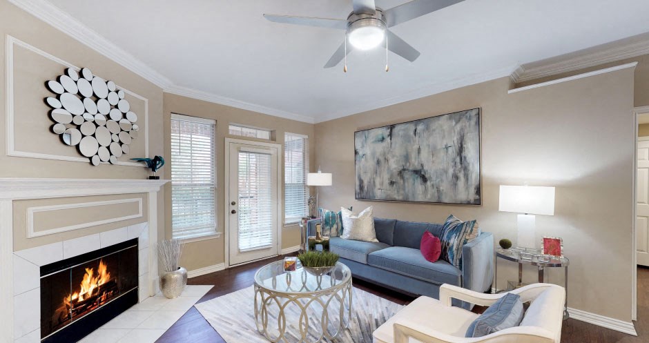 Spacious living room with wood-burning fireplace, French door, and crown molding at The Saxony Apartments