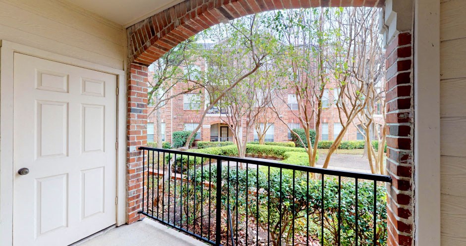 Gated luxury apartment community in north Dallas with red brick exteriors, large patio, and beautiful landscaping at The Saxony Apartments