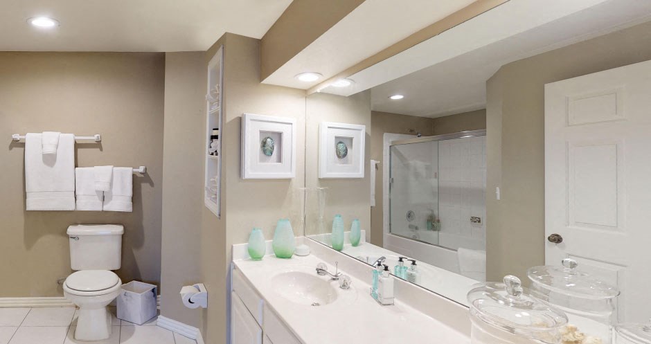 Luxury apartments with spacious bathrooms with tiled floors, linen closet, oval soaking tubs, built-in vanity, cultured marble vanity, glass shower and white cabinets in at The Saxony Apartments