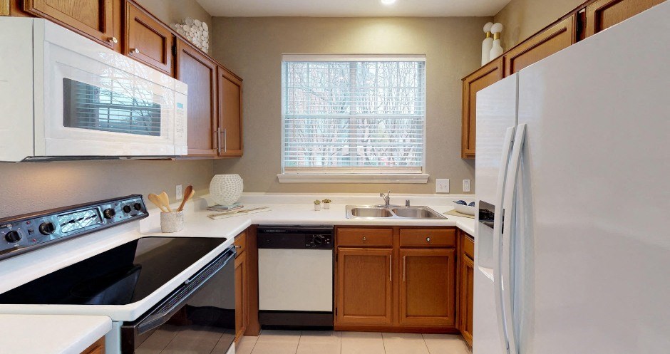 U-shaped kitchen with lots of cabinet space, lots of counter space, and a side-by-side refrigerator at The Saxony Apartments in north Dallas