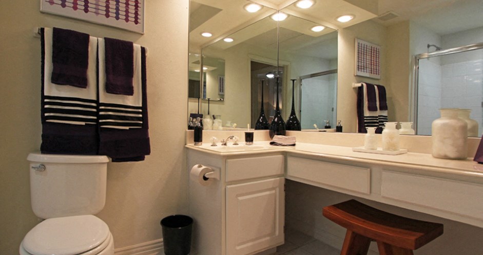 Spacious bathroom with oval soaking tub with glass enclosure, cultured marble vanity, glass shower, and built-in vanity at Tuscany Oaks Apartments in Houston.
