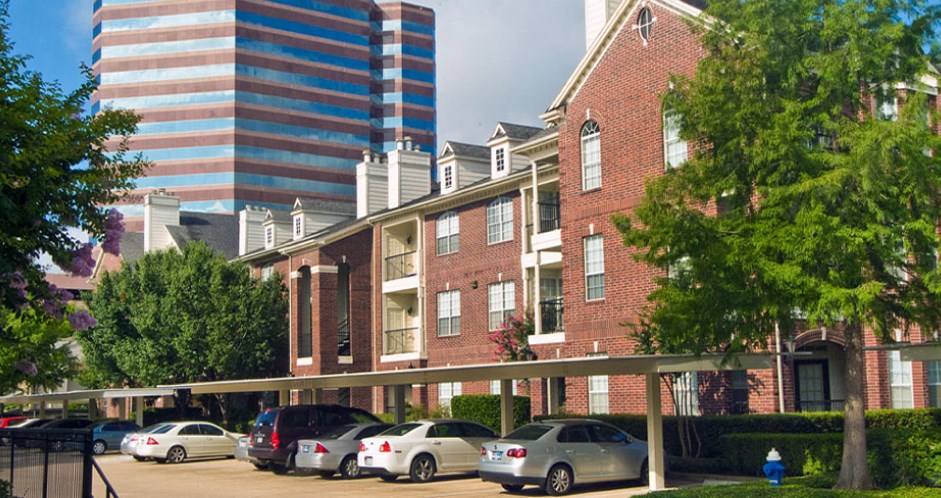Luxury apartments in a gated community with covered carports and red brick exteriors at Tuscany Oaks Apartments in Houston.