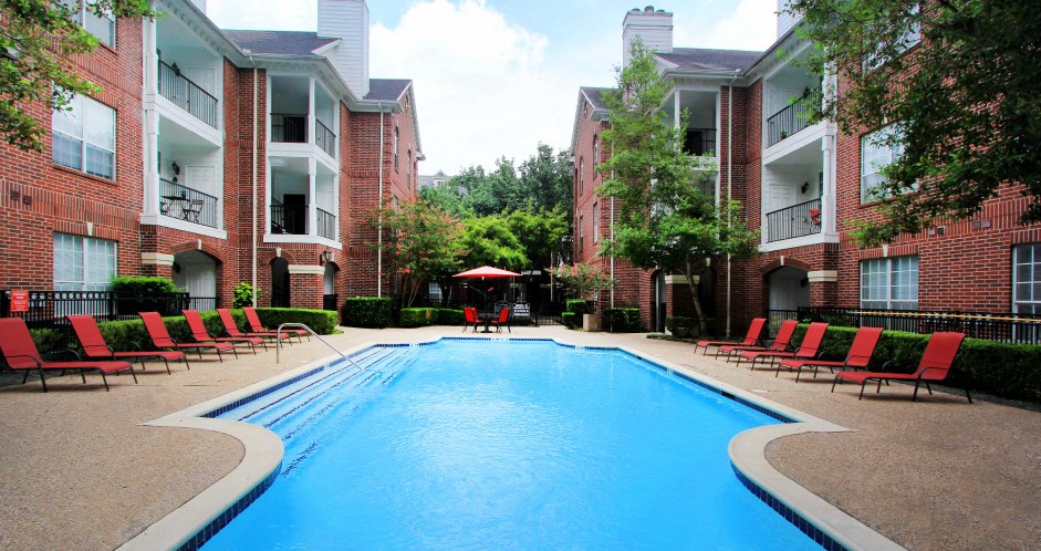 Luxury swimming pool with spacious sundeck, beautiful landscaping, and poolside lounge seating at Tuscany Oaks Apartments in Houston.