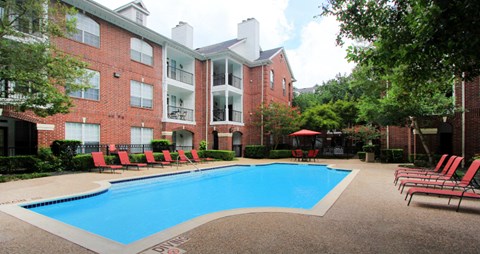 Luxury swimming pool with spacious sundeck, beautiful landscaping, and poolside lounge seating at Tuscany Oaks Apartments in Houston.