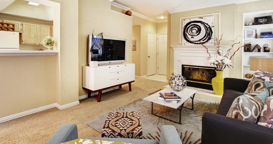 Spacious living room with wood-burning fireplace, built-in bookshelves, crown molding, and 9-foot ceilings at Tuscany Oaks Apartments in Houston.