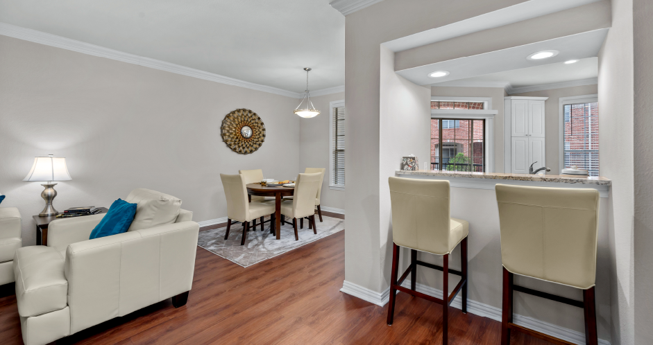 Spacious dining room with built-in bookshelves, hardwood floors, breakfast bar, and French doors at Tuscany Villas Apartments in Houston.