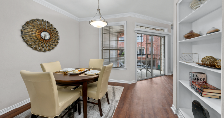 Spacious dining room with built-in bookshelves, hardwood floors, and French doors at Tuscany Villas Apartments in Houston.
