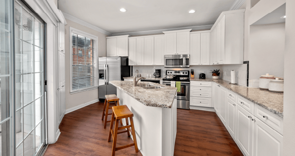 Spacious kitchen with island, granite countertops, custom home cabinets, French doors, smooth glass top stove, spacious pantries, breakfast bar and stainless-steel appliances at Tuscany Row Townhomes in Houston.
