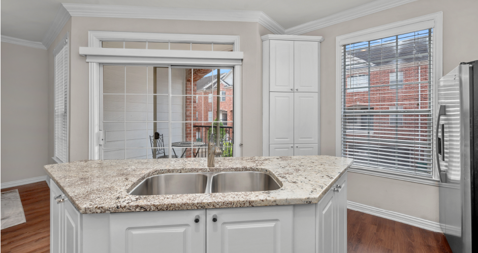 Spacious kitchen with island, granite countertops, custom home cabinets, French doors, smooth glass top stove, spacious pantries, and stainless-steel appliances at Tuscany Villas in Houston.