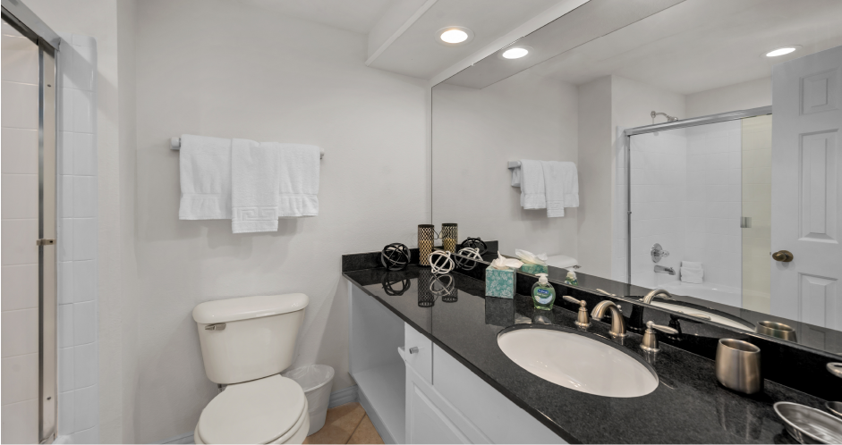 Luxury bathroom with oval soaking tub with glass enclosure, granite vanity top, and glass shower at Tuscany Lane Apartments in Houston.