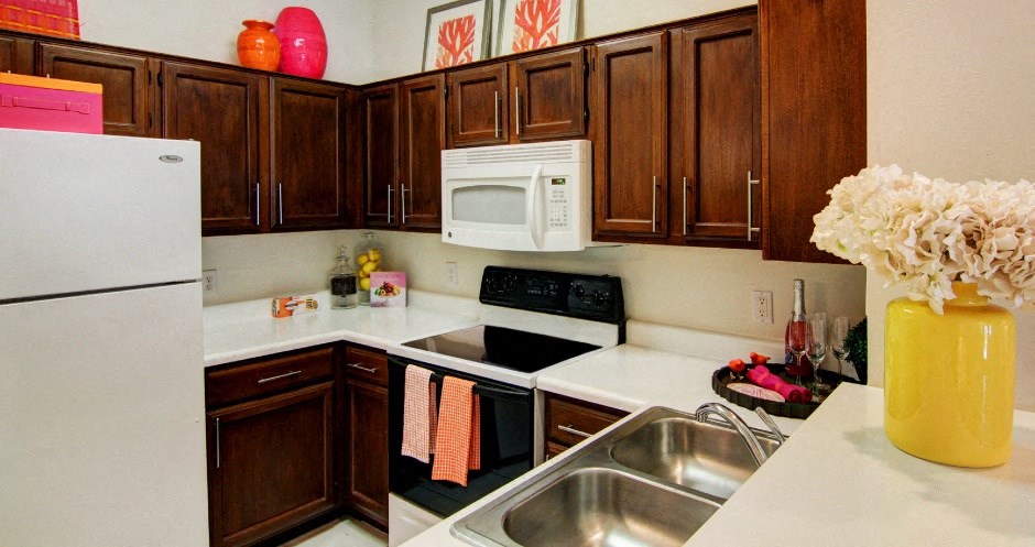 Spacious kitchen with honey brown toned cabinets with modern silver hardware, and white appliances