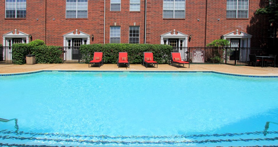 Luxury swimming pool with spacious sundeck, beautiful landscaping, and poolside lounge seating at Tuscany Villas in Houston.