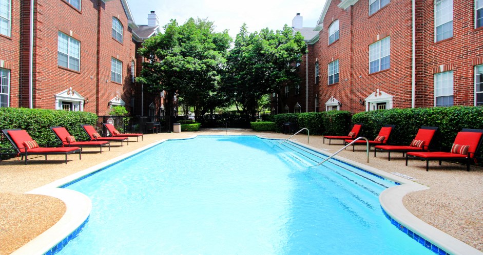 Luxury swimming pool with spacious sundeck, beautiful landscaping, and pool-side lounge seating at Tuscany Villas in Houston.