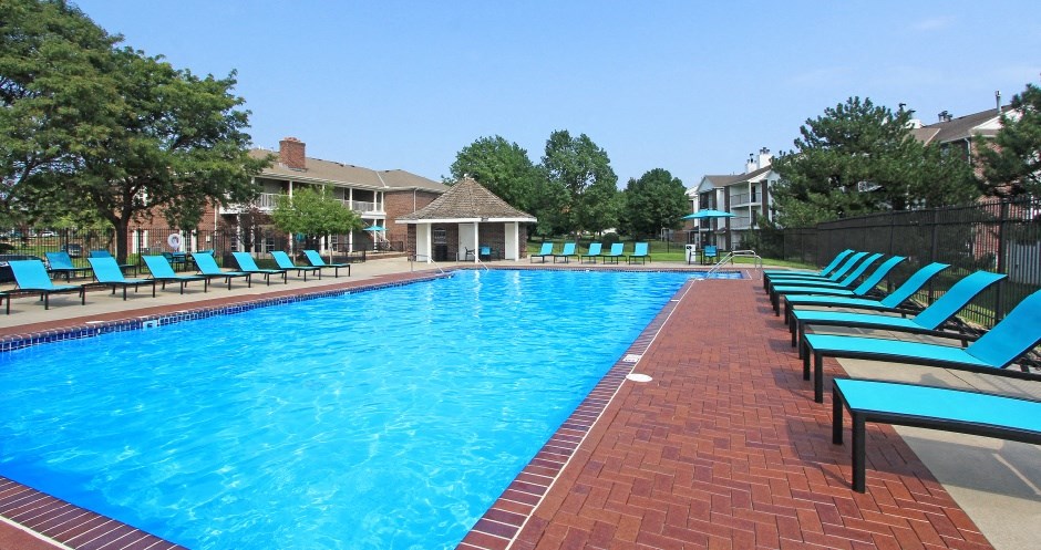 Huge swimming pool with spacious sundeck, poolside lounge chairs, beautiful landscaping, and scenic views at The Vanderbilt Apartments in Omaha, Nebraska