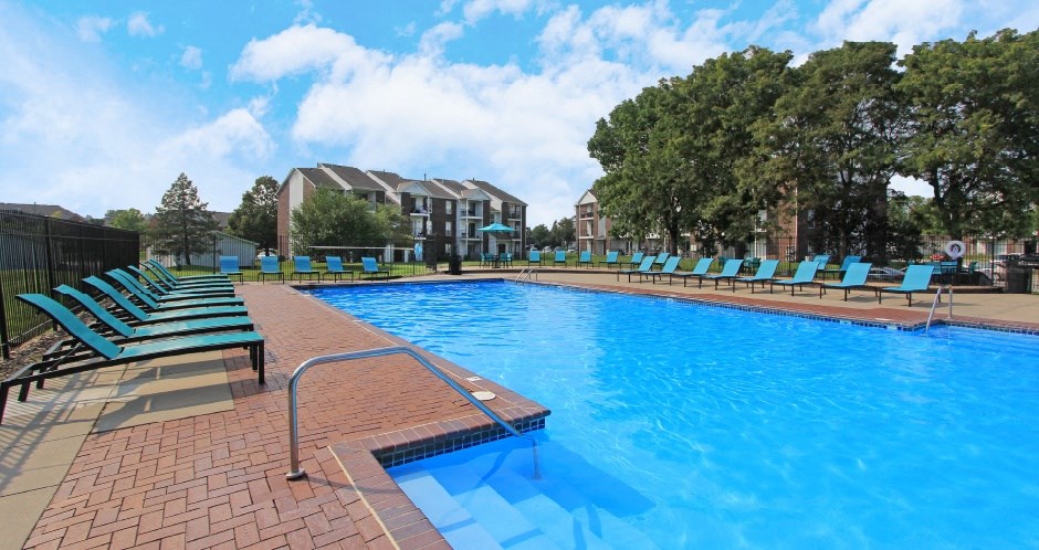Huge swimming pool with spacious sundeck, poolside lounge chairs, beautiful landscaping, and scenic views at The Vanderbilt Apartments in Omaha, Nebraska