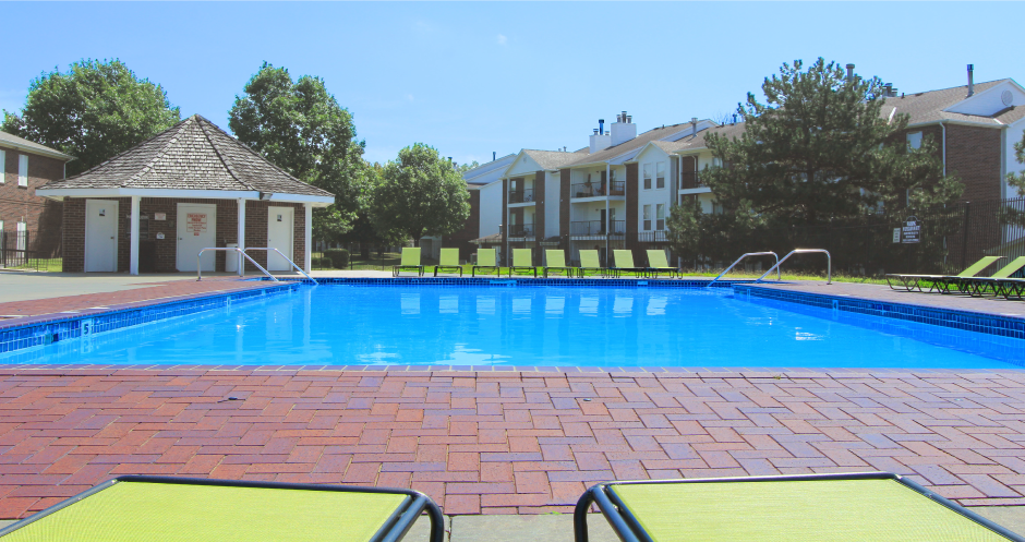 Huge swimming pool with spacious sundeck, poolside lounge chairs, beautiful landscaping, and scenic views at The Vanderbilt Apartments in Omaha, Nebraska