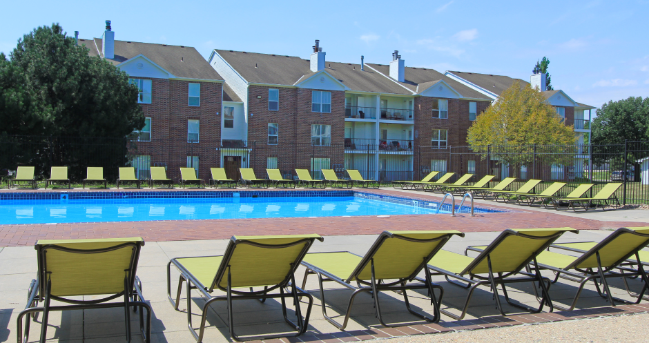 Huge swimming pool with spacious sundeck, poolside lounge chairs, beautiful landscaping, and scenic views at The Vanderbilt Apartments in Omaha, Nebraska