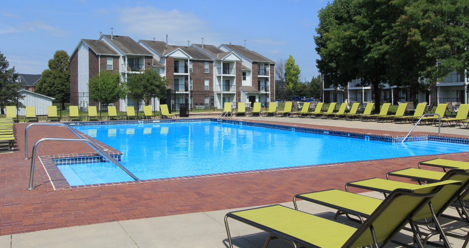 Huge swimming pool with spacious sundeck, poolside lounge chairs, beautiful landscaping, and scenic views at The Vanderbilt Apartments in Omaha, Nebraska