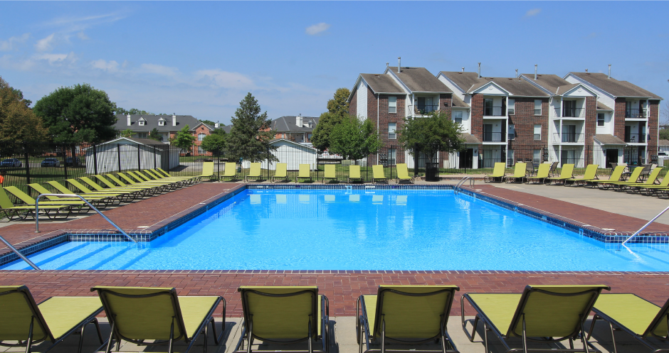 Huge swimming pool with spacious sundeck, poolside lounge chairs, beautiful landscaping, and scenic views at The Vanderbilt Apartments in Omaha, Nebraska