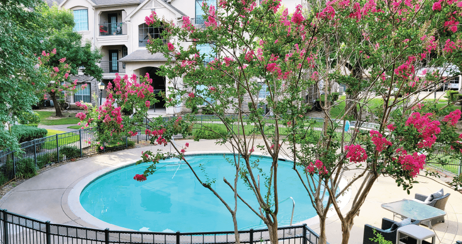 Luxury resort-style swimming pool with fountain, poolside lounges chairs, beautiful landscaping, lush landscaping and scenic views at Village on the Parkway Apartments.