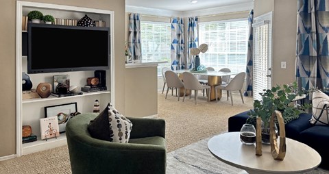 A living room with a green armchair and a television on a white stand.