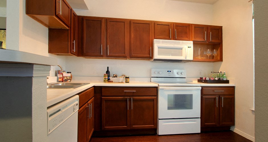 Spacious kitchen with designer white appliances and plank wood floors at Village on the Parkway Apartments.