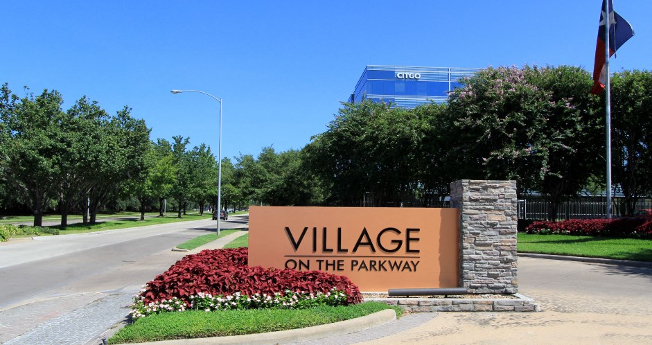 a sign for village on the parkway in front of a road