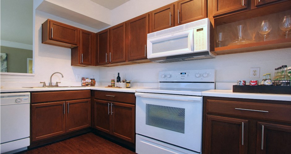 Spacious kitchen with designer white appliances and plank wood floors at Village on the Parkway Apartments.