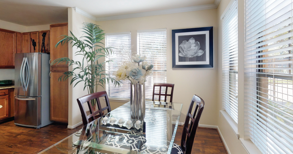 Luxury apartments in Houston with spacious kitchen and dining room with granite countertops, kitchen island, stainless steel appliances, oversized windows, lots of natural light, and hardwood floors.