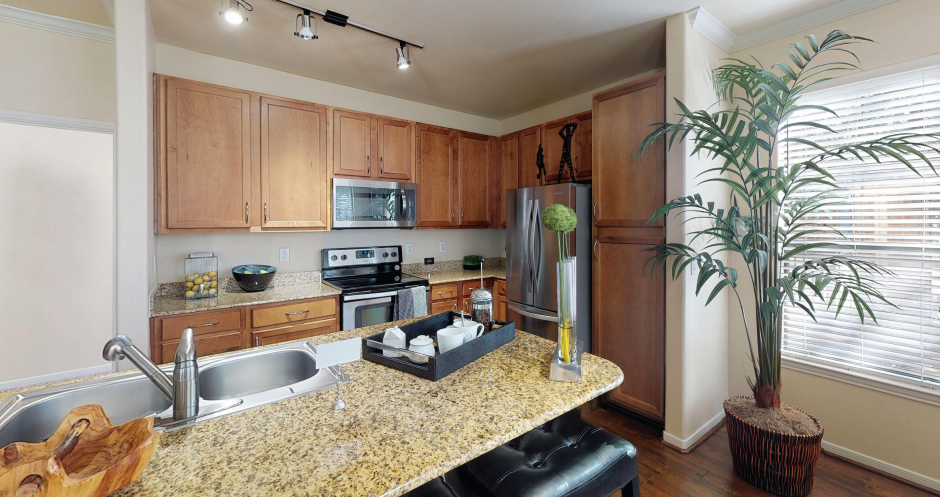 Luxury apartments with hardwood floors, granite countertops, side-by-side refrigerator, and stainless appliances at The Voss Apartments in Houston.