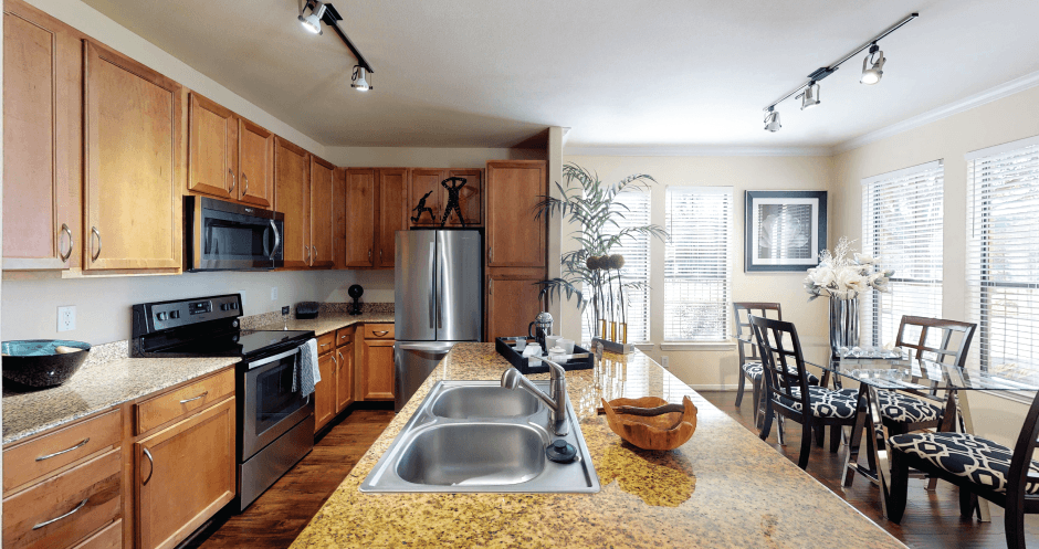 Luxury apartments in Houston with spacious kitchen and dining room with granite countertops, kitchen island, stainless steel appliances, oversized windows, lots of natural light, and hardwood floors.