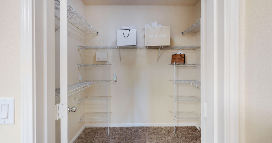 a walk in closet with shelves and bags