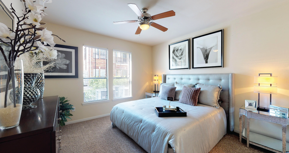 Spacious master bedroom with attached master bathroom, walk-in closet, and ceiling fan at The Voss Apartments in Houston.