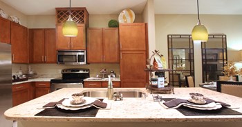 Luxury apartments next to the Galleria in Dallas with granite countertops, stainless steel appliances, built-in wine rack, kitchen island, and porcelain tile floor at Villa Piana Apartments in Dallas - Photo Gallery 26