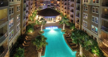 Luxury apartments with resort-style pool, palm trees, spacious sundeck with poolside lounge chairs, grilling station, fountains, and fitness center at Villa Piana Apartments in Dallas - Photo Gallery 3