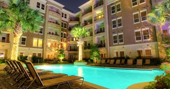 Luxury apartments with resort-style pool, palm trees, spacious sundeck with poolside lounge chairs, grilling station, fountains, and fitness center at Villa Piana Apartments in Dallas - Photo Gallery 36