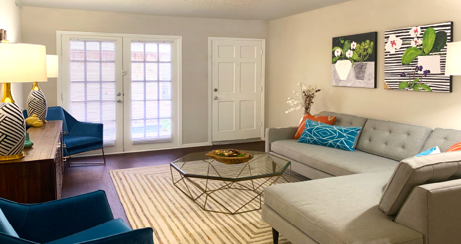 Spacious one and two bedroom floor plans with white brick accent walls, wood plank floors, and French doors at Waters of Winrock Apartments in Houston.