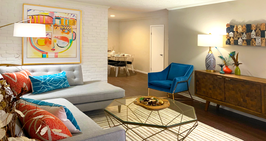 Spacious one and two bedroom floor plans with white brick accent walls and wood plank floors at Waters of Winrock Apartments in Houston.