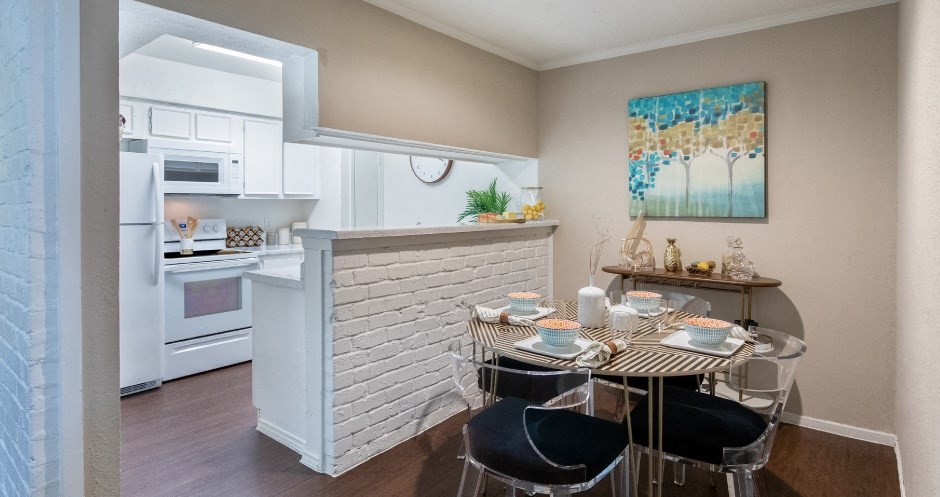 Spacious one and two bedroom floor plans with white brick accent walls and wood plank floors at Waters of Winrock Apartments in Houston