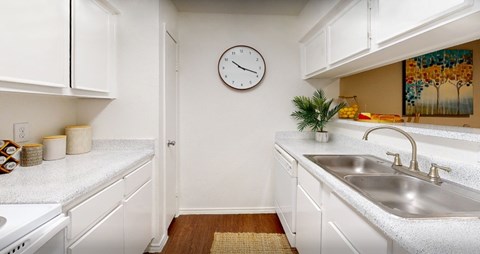 Bright white kitchens with wood plank floors at Waters of Winrock Apartments in Houston