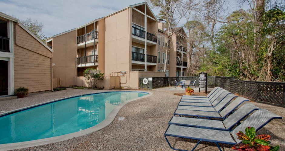 Gated apartments with 2 swimming pools, convenient bayou location, lush landscaping, and scenic views at Woodlake Oaks Apartments in Houston.