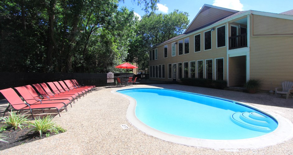 Gated apartments with 2 swimming pools, convenient bayou location, lush landscaping, and scenic views at Woodlake Oaks Apartments in Houston.