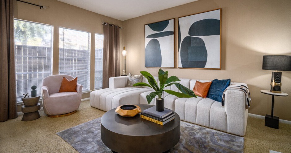 Spacious living room with oversized windows, lots of natural light, and woodburning fireplace at Woodlake Oaks Apartments in Houston
