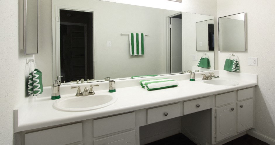 Spacious bright white bathroom with extra cabinet and storage space and built-in vanity at Woodlake on the Bayou Apartments in Houston.