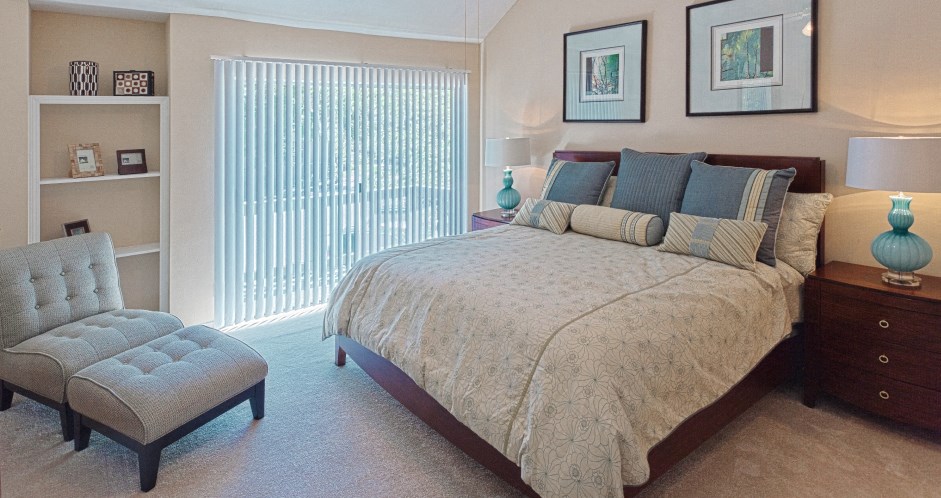 Huge master bedroom with vaulted ceiling, built-in shelves, attached master bathroom and walk-in closet at Woodlake on the Bayou Apartments in Houston.
