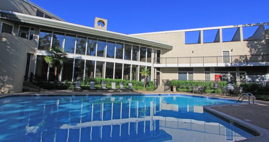 Gated apartments with 4 swimming pools, convenient bayou location, lush landscaping and scenic views at Woodlake on the Bayou Apartments in Houston.