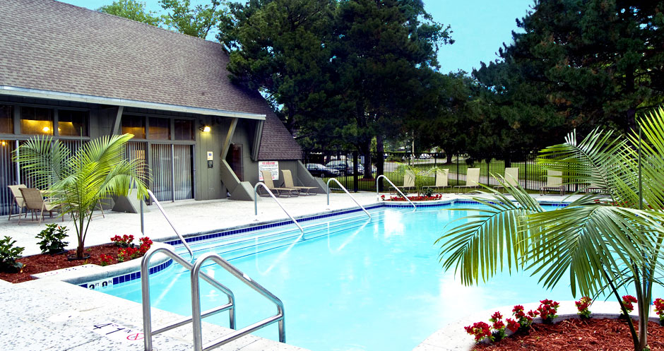 Large swimming pool with poolside lounge chairs, beautiful landscaping, park-like setting, scenic views, and luxury resident clubhouse at Alpine Village Apartments in La Vista, Nebraska