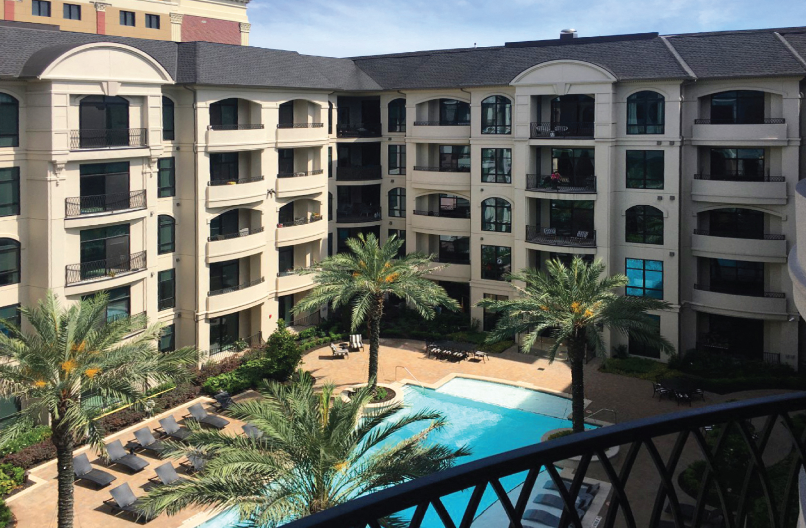Luxury apartments with resort-style pool with palm trees, Baja shelf, fountains, lap lane, outdoor lounges, and grilling station at Le Palais Apartments in Houston.