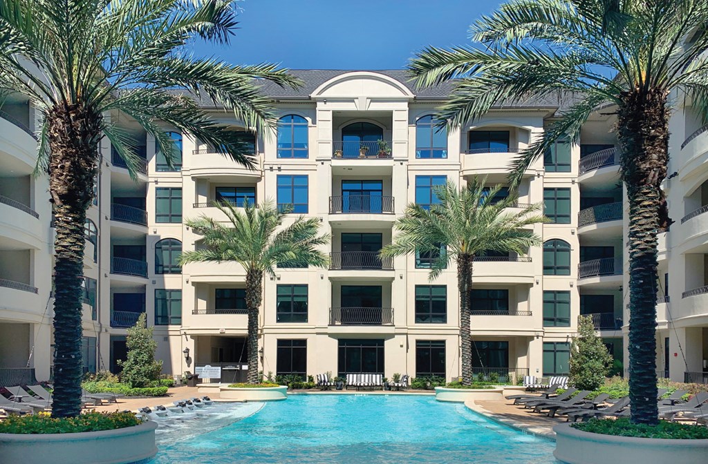 Luxury apartments with resort-style pool with palm trees, Baja shelf, fountains, lap lane, outdoor lounges, and grilling station at Le Palais Apartments in Houston.