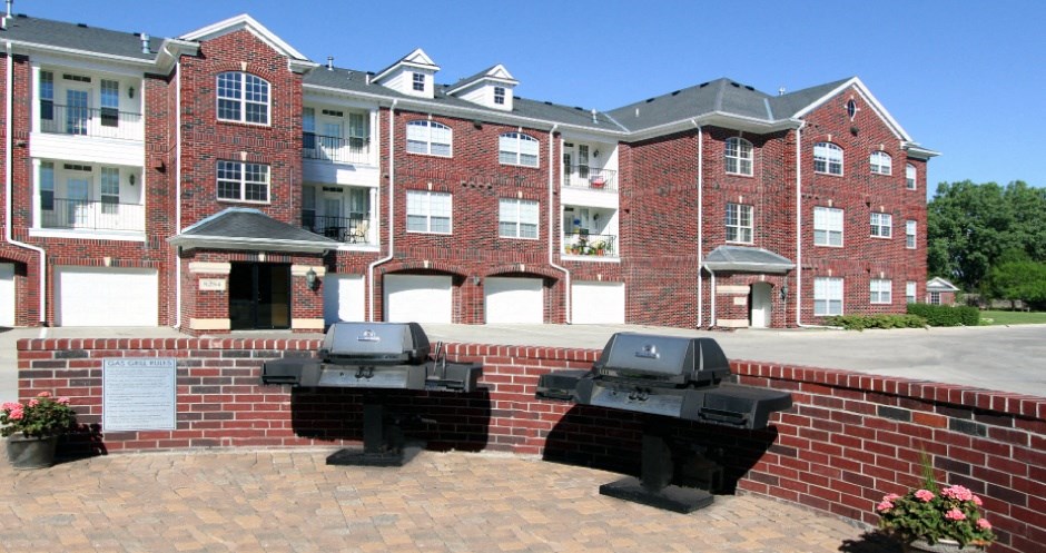 Luxury apartments with red brick exteriors, resident grilling station, and attached garages at Rockledge Oaks Apartments in Lincoln, Nebraska
